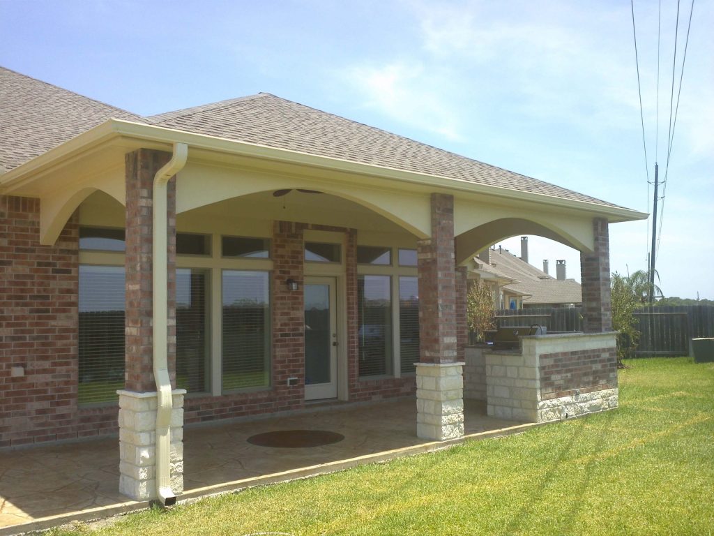 Custom patio cover with a shaded seating area behind a Houston home