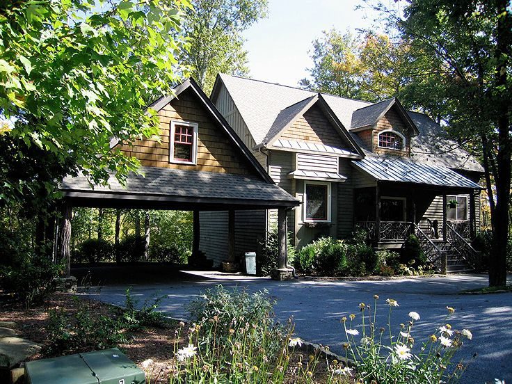 House with an attached carport cover and garden beds along the drive