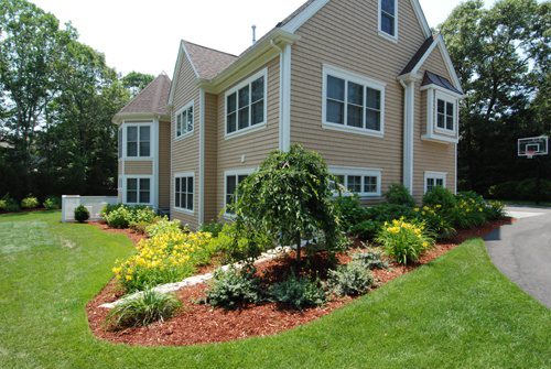 Beige sided colonial with a planted bed across the front