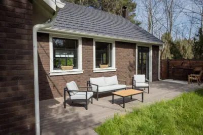 Brick house with a new wing and a small seating area beside it