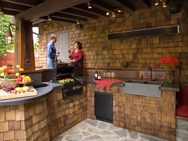 Covered outdoor kitchen with counters, a sink and a fridge