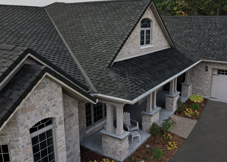 Dark shingle roof over a stone and siding home with dormers