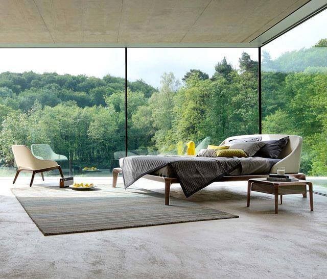 Room with a floor to ceiling glass wall looking out at trees and water