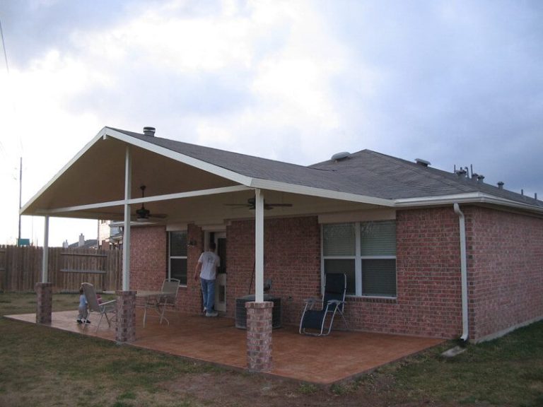 Patio cover shading a paved seating area behind a house