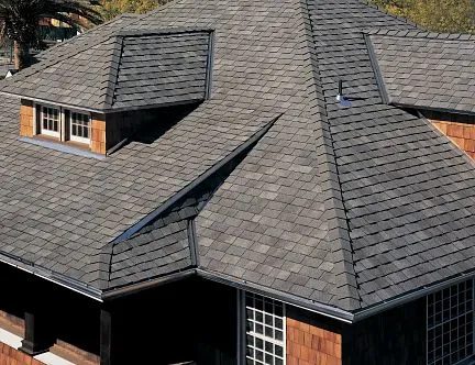 Close view of a home's gray laminated shingle roof with a dormer window and multiple hips and valleys