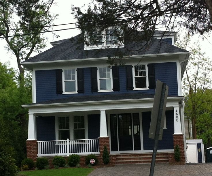 Navy lap siding and white trim on a two story house with a porch
