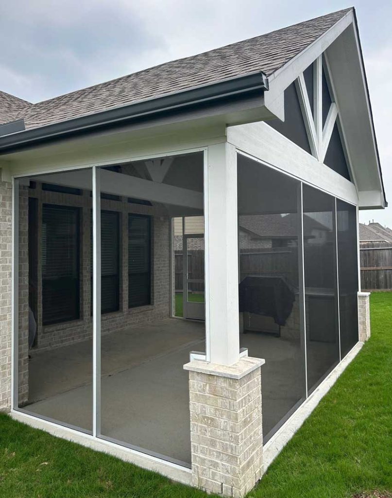 Screened patio enclosure with a peaked roof attached to the back of a house