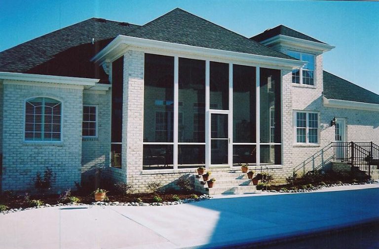 Tall screened room on a brick home beside a pool