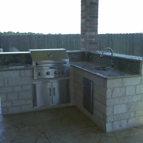 Stone outdoor kitchen with a built in grill and a sink