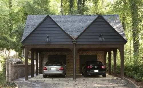 Two-bay wooden carport with a gabled shingle roof sheltering two parked cars