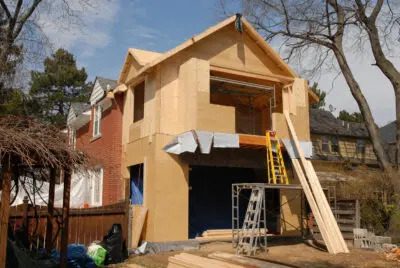 Two story addition under construction with fresh sheathing and a ladder