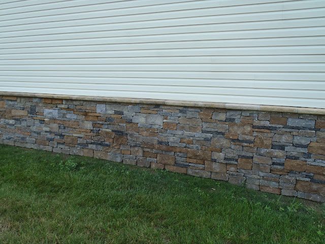 White lap siding above a stacked stone base