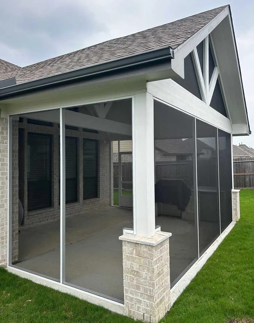 Screened patio enclosure on the back of a brick home with white posts on brick bases and a gabled roof