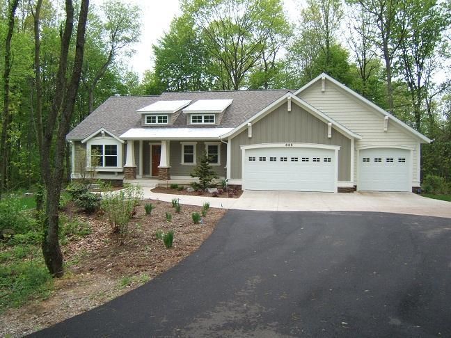 New siding and stone on a home set back among tall trees