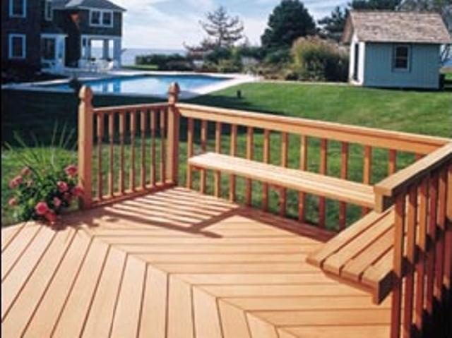 Wooden deck with built in benches beside a backyard pool