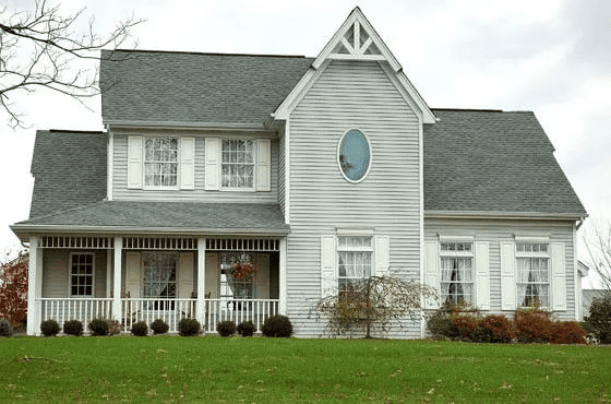 Two story home with white lap siding, gray shingle roof and a covered front porch with white railings